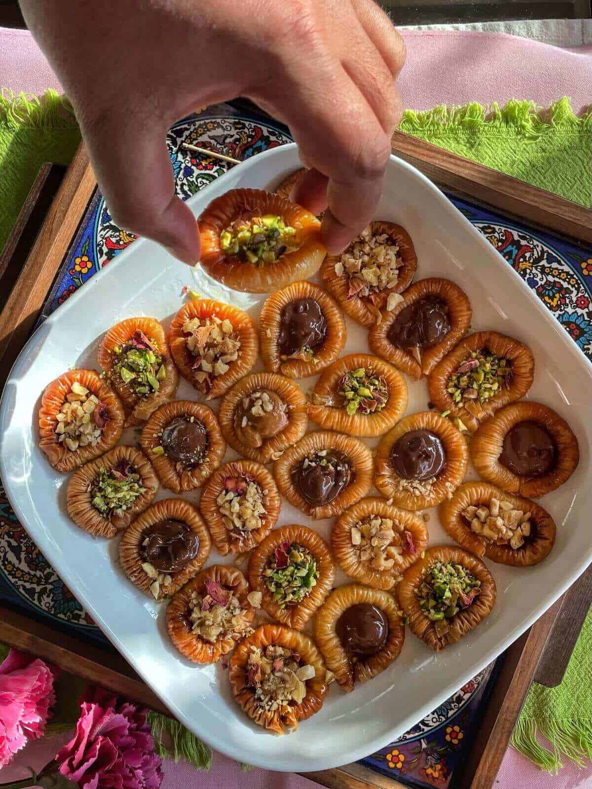 The Mr. picking one of bracelet baklava from the platter