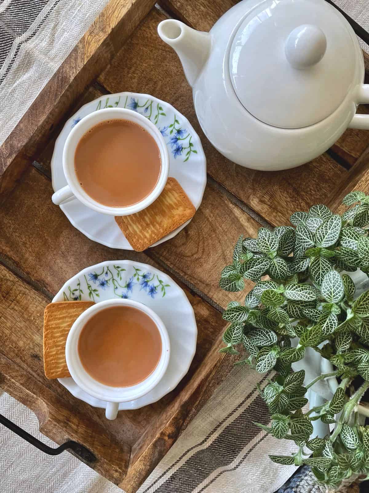 two cups of masala chai served with biscuits
