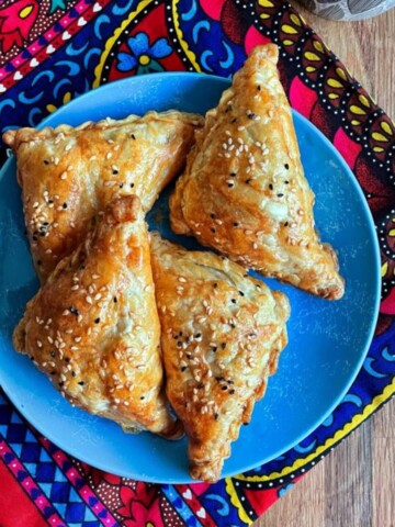 three puff pastry afghan samosas on a blue plate.