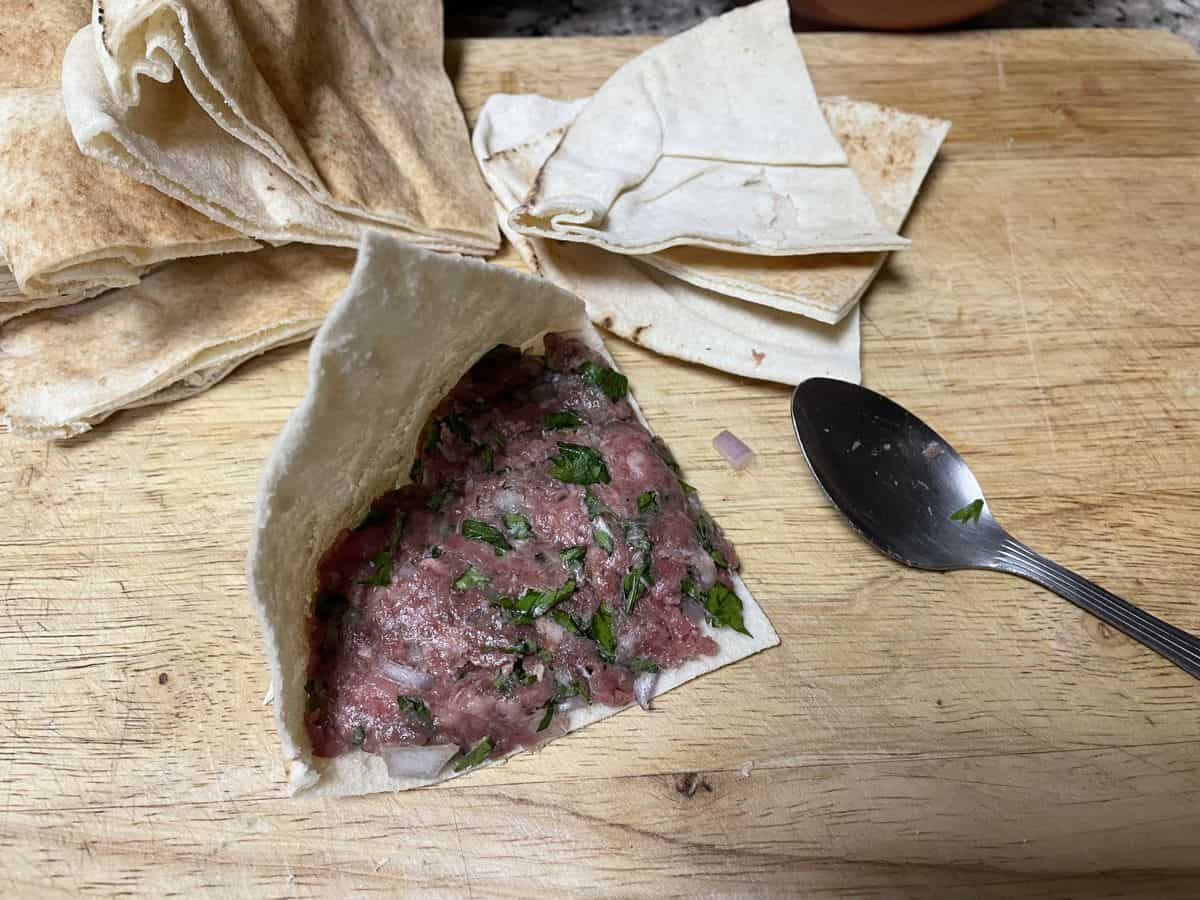 a pita triangle piece with meat mixture spread on one side