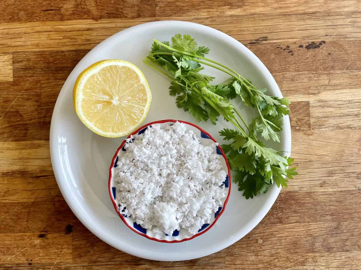 grated coconut, lime and coriander leaves on a plate