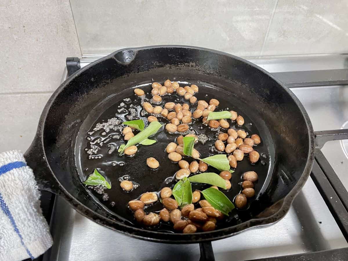 peanuts, mustard seeds and curry leaves in a skillet