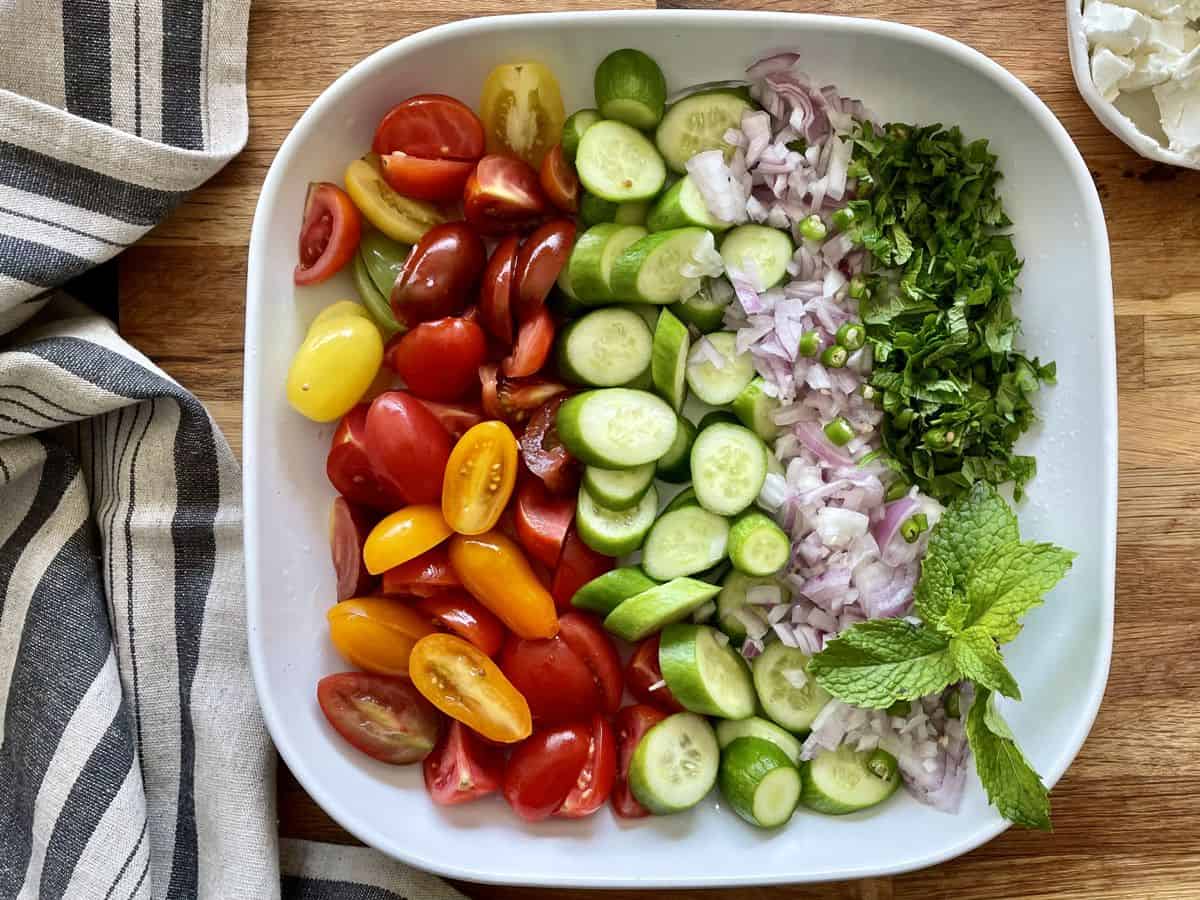 A platter with chopped veggies for the cucummber tomato salad. 