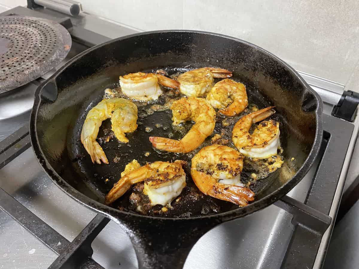 pan frying marinated prawns in a skillet. 