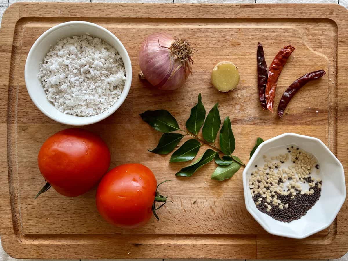 Ingredients for tomato chutney with coconut are displayed on a cutting board. 