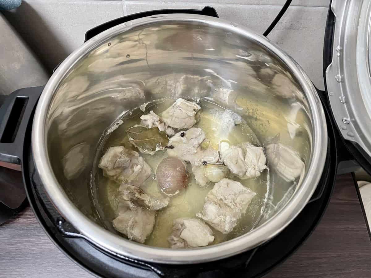 An open instant pot that has cooked chicken broth.
