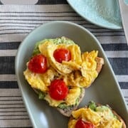 Scrambled eggs with tomatoes on a avocado toast.
