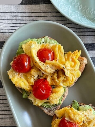 Scrambled eggs with tomatoes on a avocado toast.