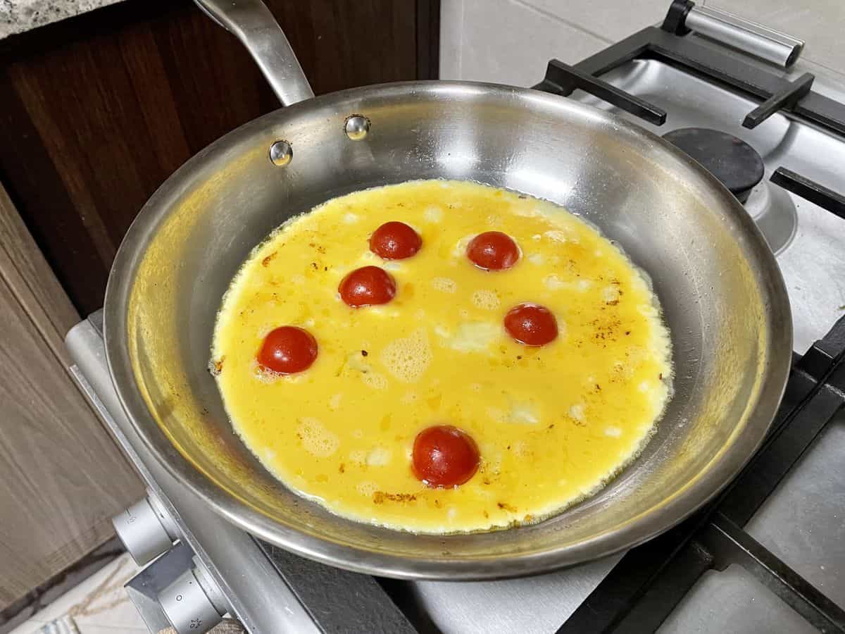 Pan with whisked egg and milk and cherry tomatoes