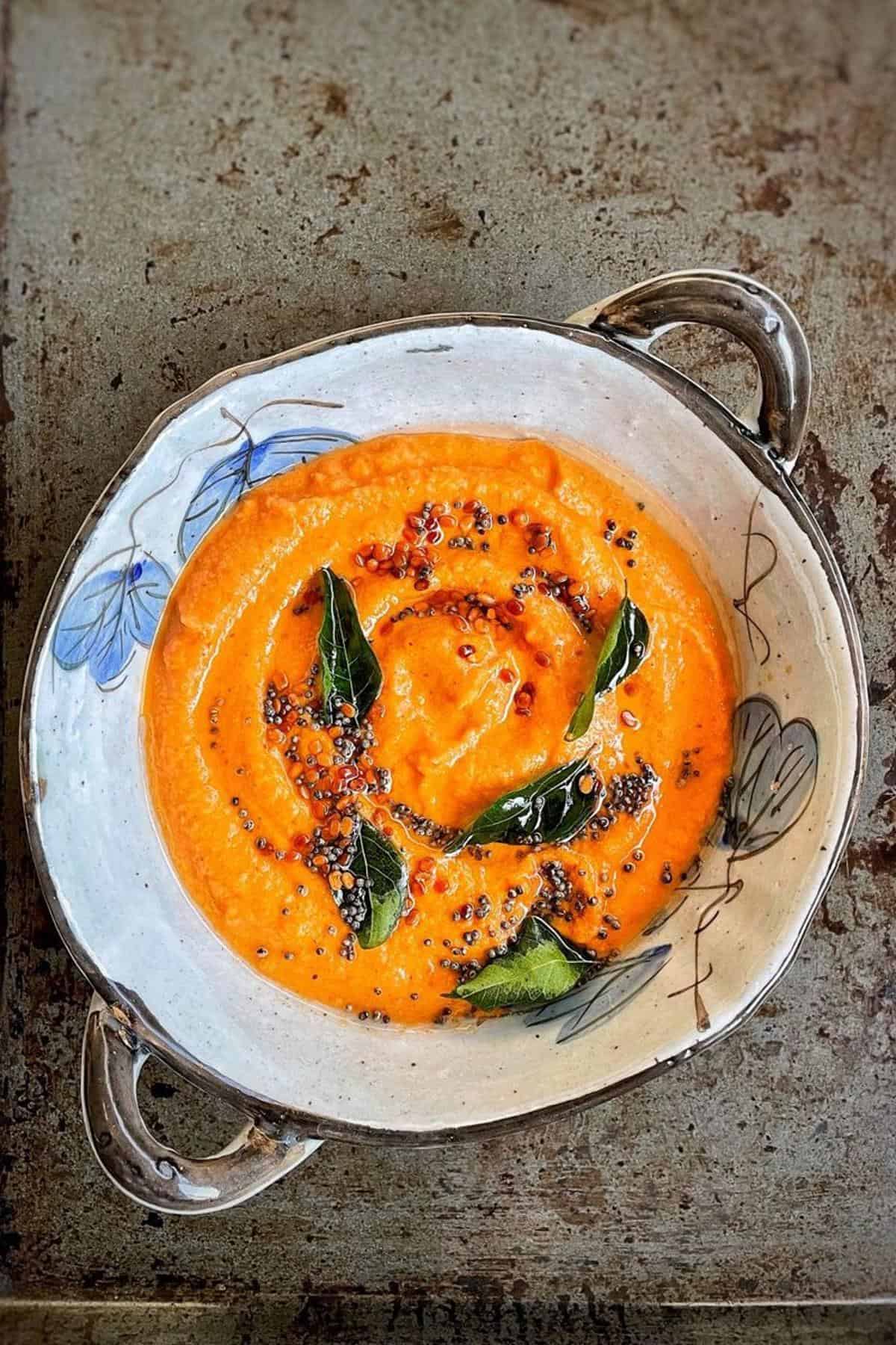 A bowl of coconut tomato chutney with tadka poured over.