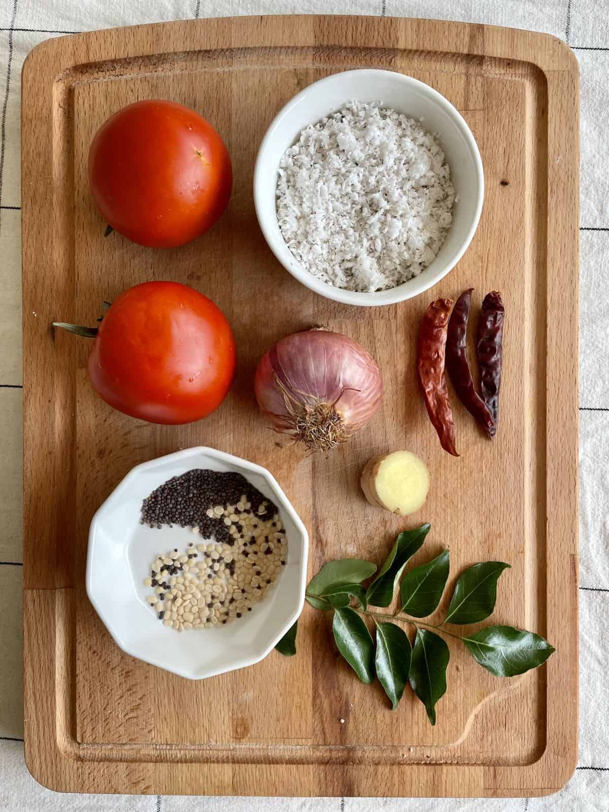 Ingredients for tomato chutney with coconut are displayed on a cutting board.