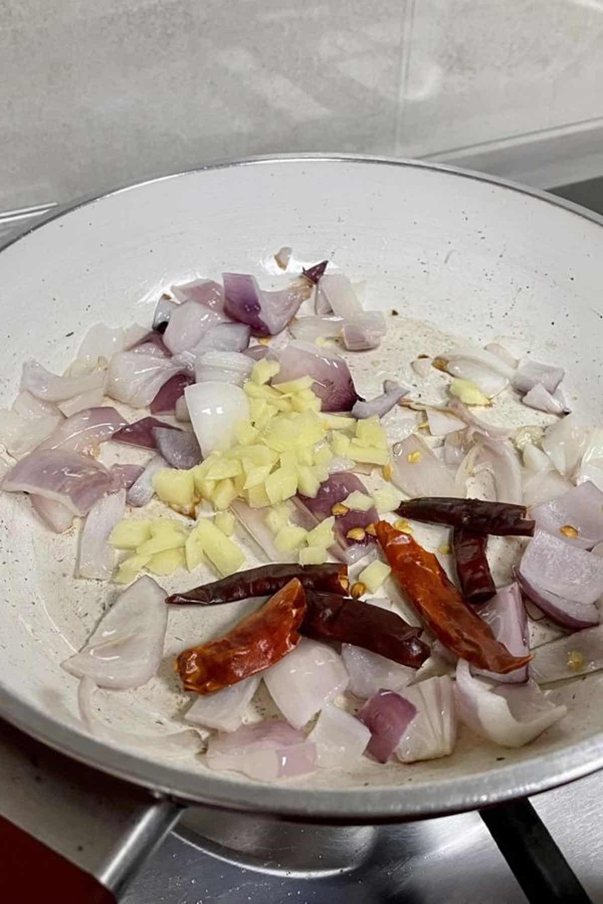 A pan on the stove with aromatics sauted in oil.