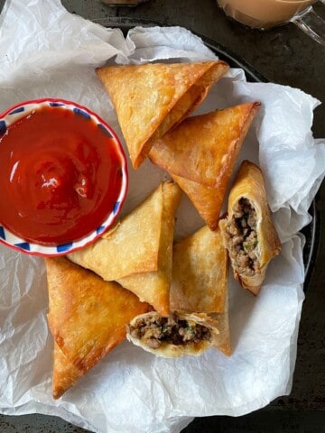 A platter of fried keema samosa served with a bowl of ketchup.