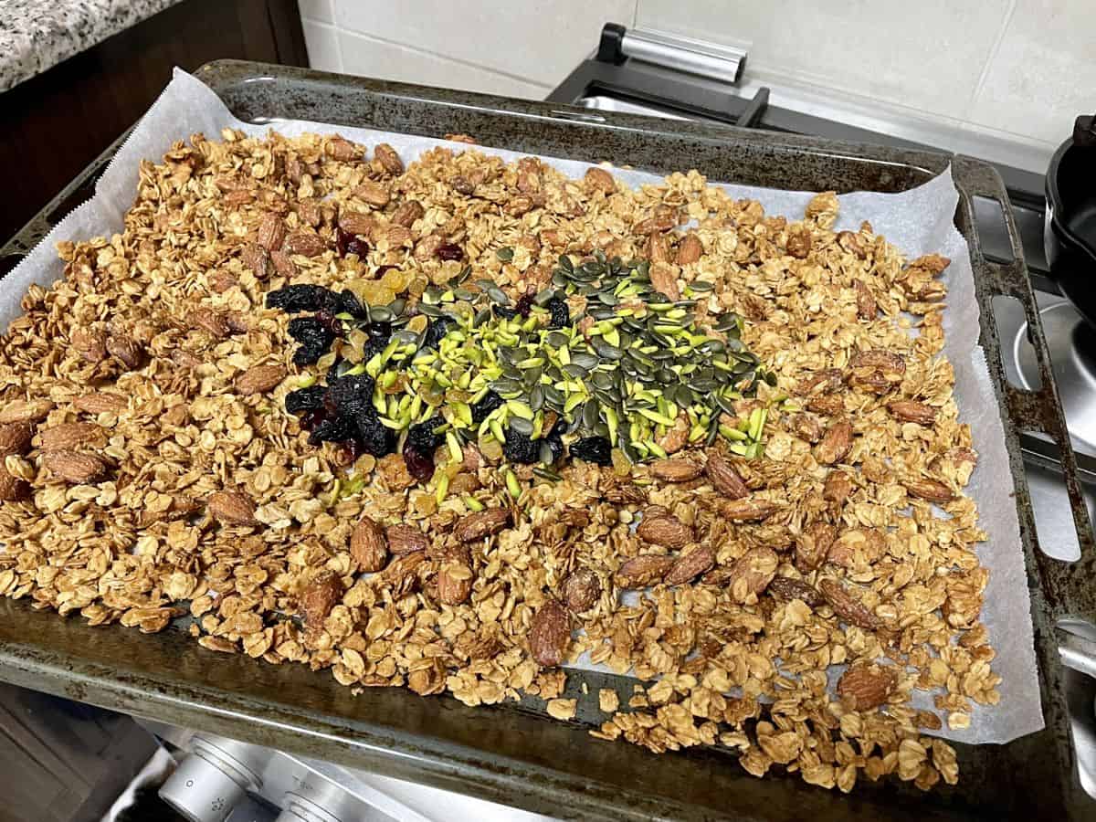 A tray of cooled granola with dried fruits and seeds.
