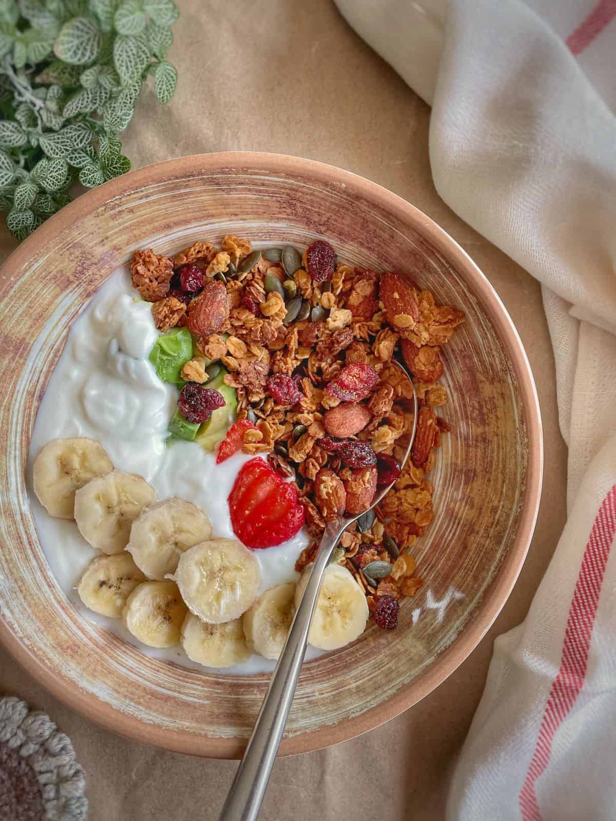 A bowl of tahini granola served with sliced banana and yogurt. 