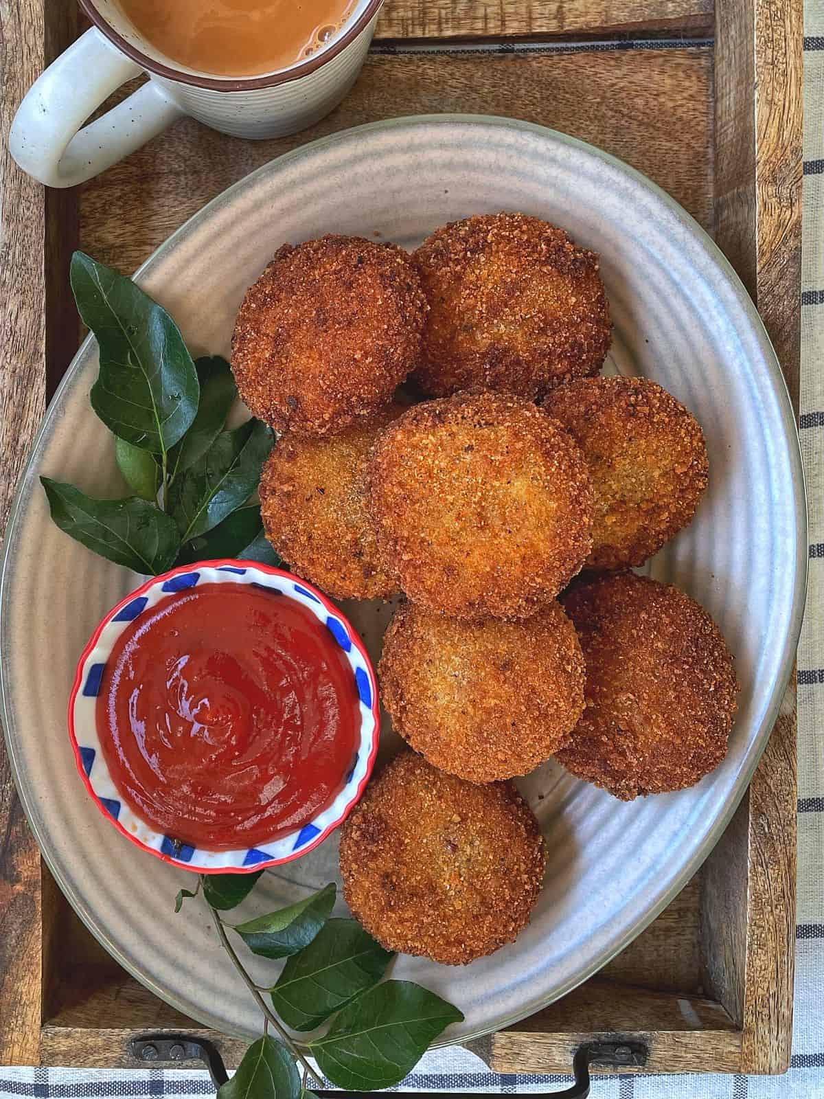 A platter of fried tuna cutlets with a small bowl of ketchup