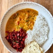A bowl of rice with Khatti Meethi dal, pappadom and sabji.