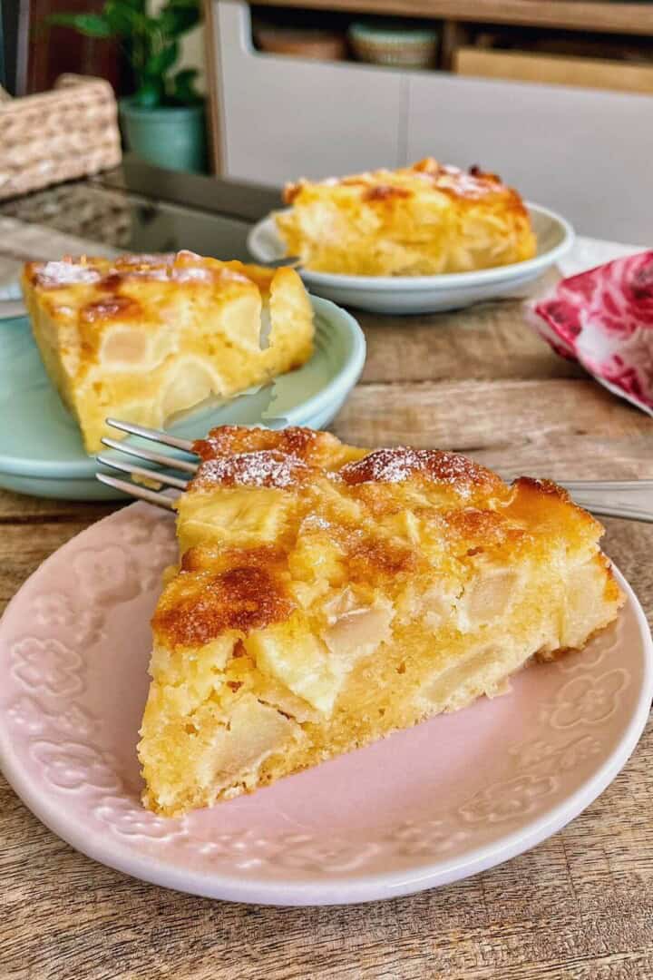A slice of rustic apple cake on a pink dessert plate.