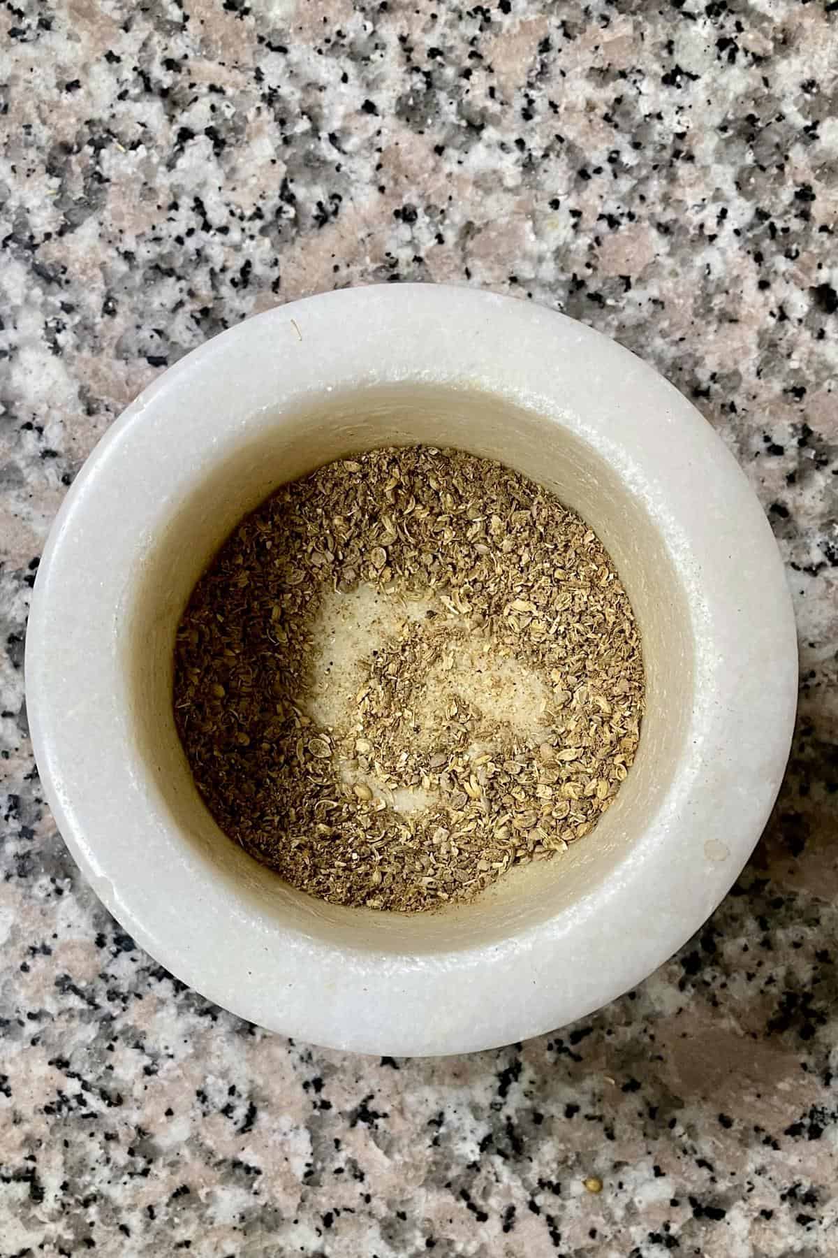 Crushed roasted coriander and cumin in a mortar and pestle.