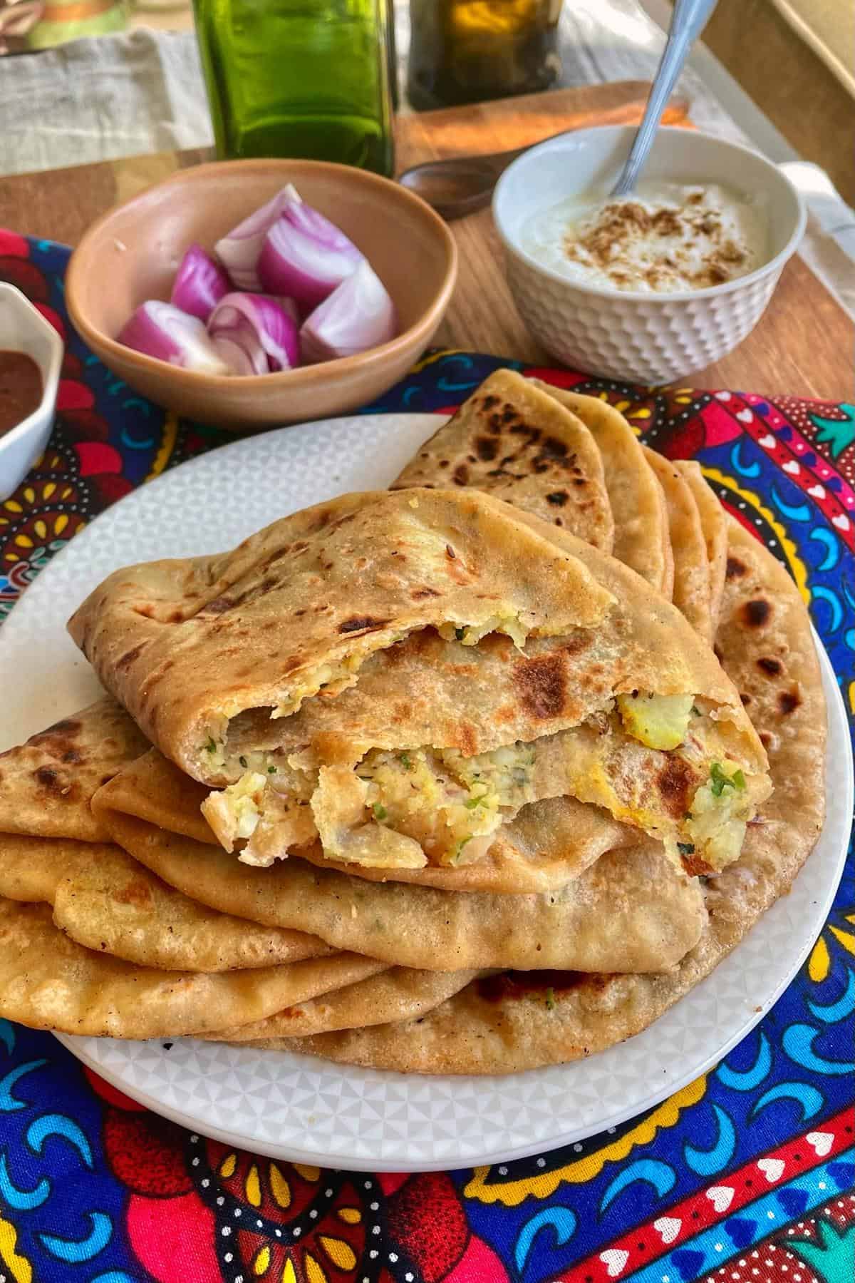 Aloo paratha stacked and one torn piece.