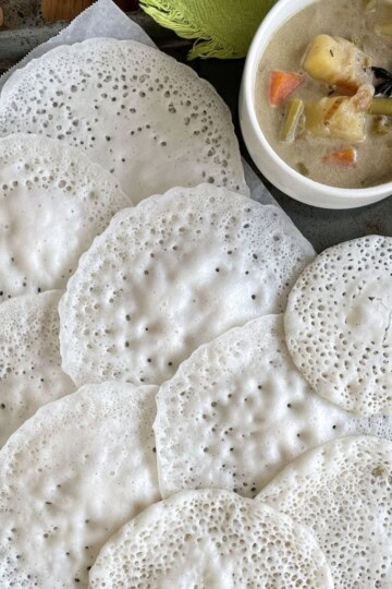 A tray of vellayappam with a bowl of stew.