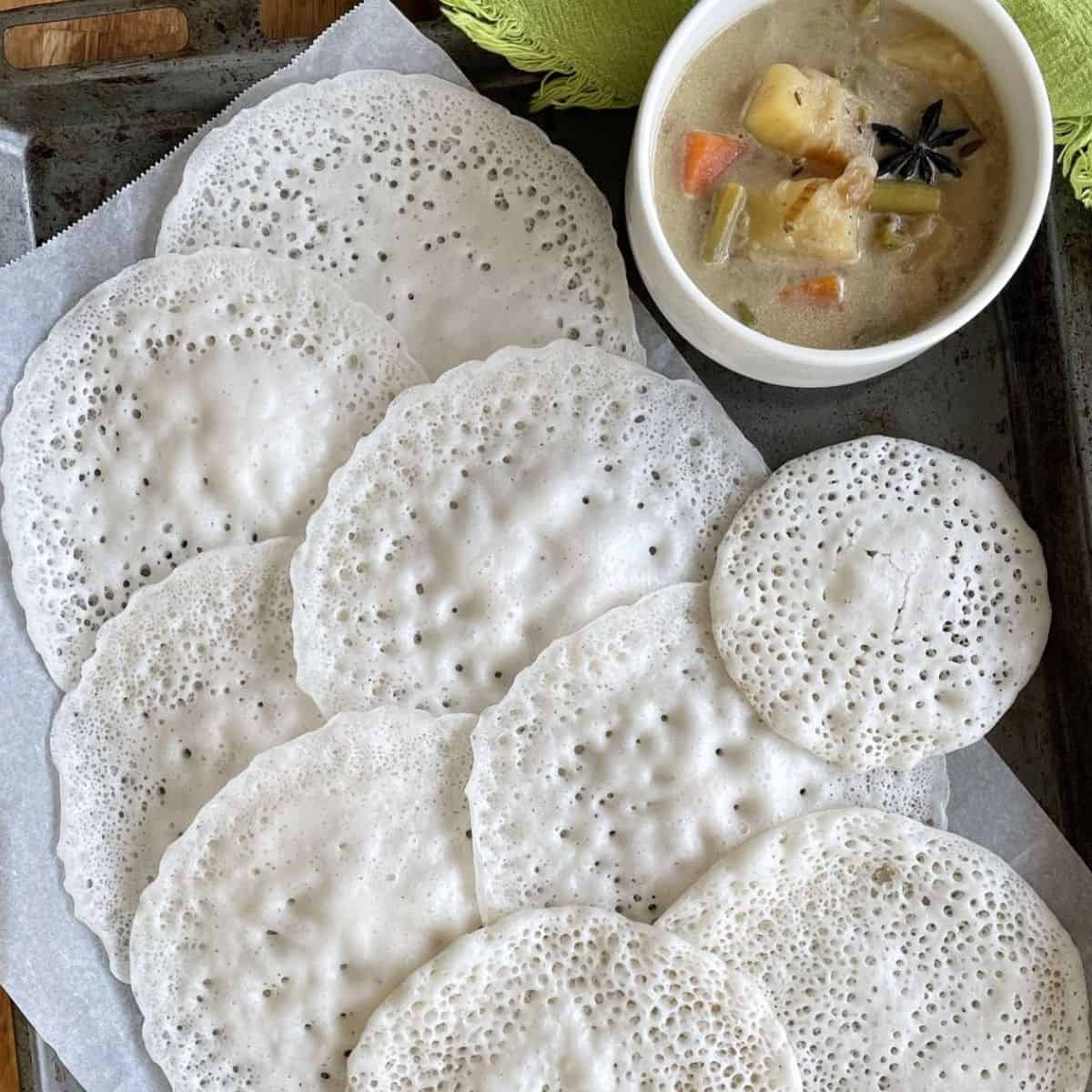 A tray of vellayappam with a bowl of stew.
