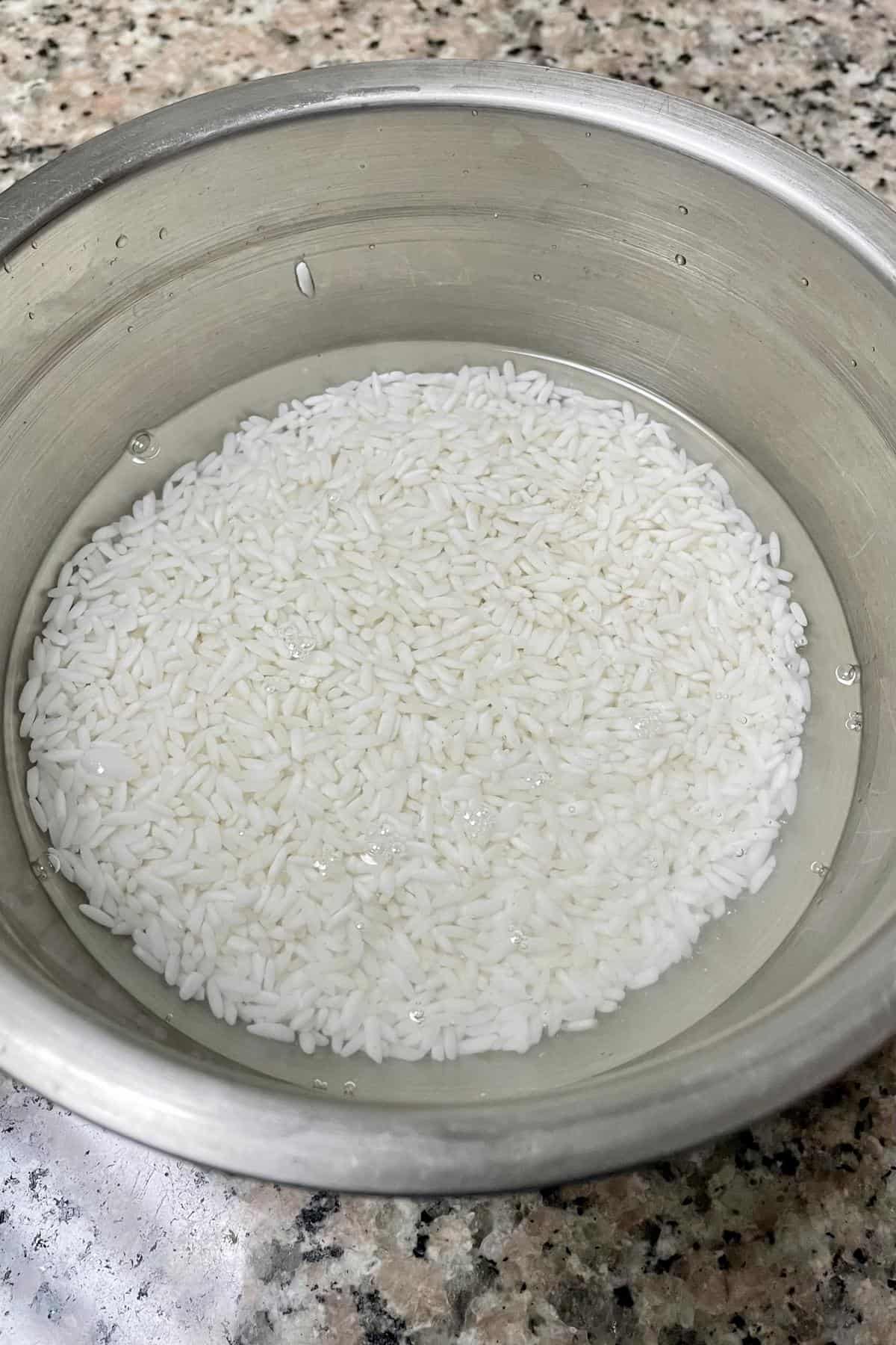 raw rice soaking in water in a metal bowl for appam. 
