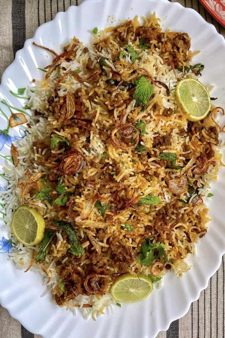 Crispy fried onion rice with lime and fresh herbs on a white platter.
