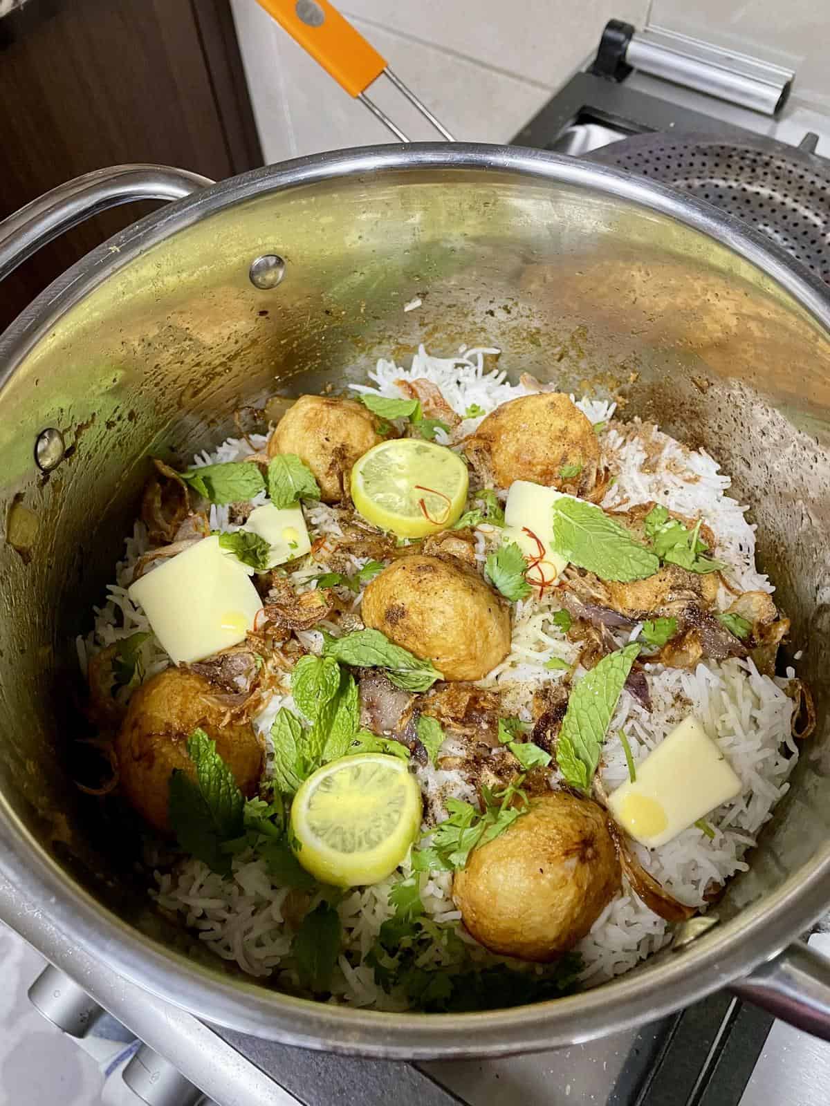 keema biryani with fried potatoes, rice, herbs, and lime garnish, perfect for a flavorful Indian meal.