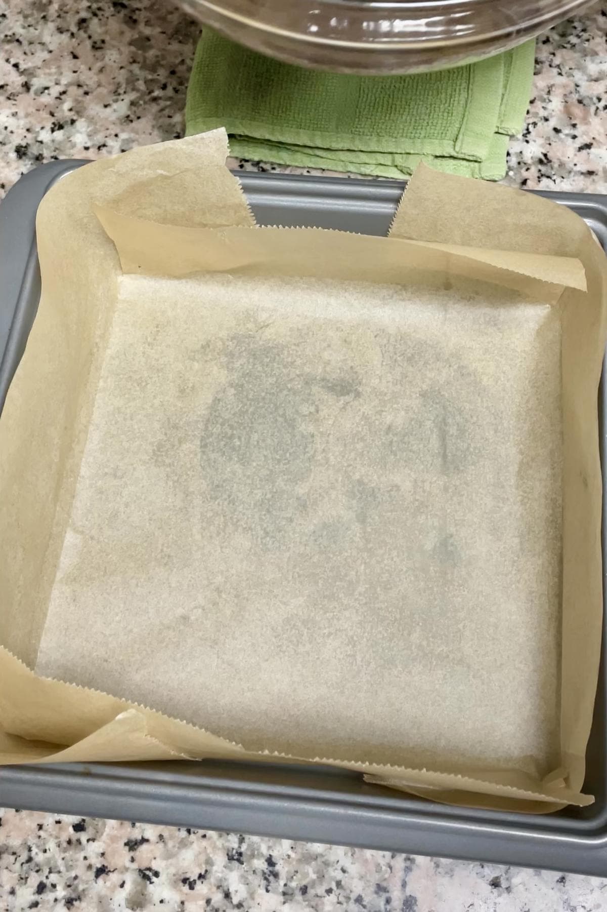 A square 8x8 pan lined with baking paper.