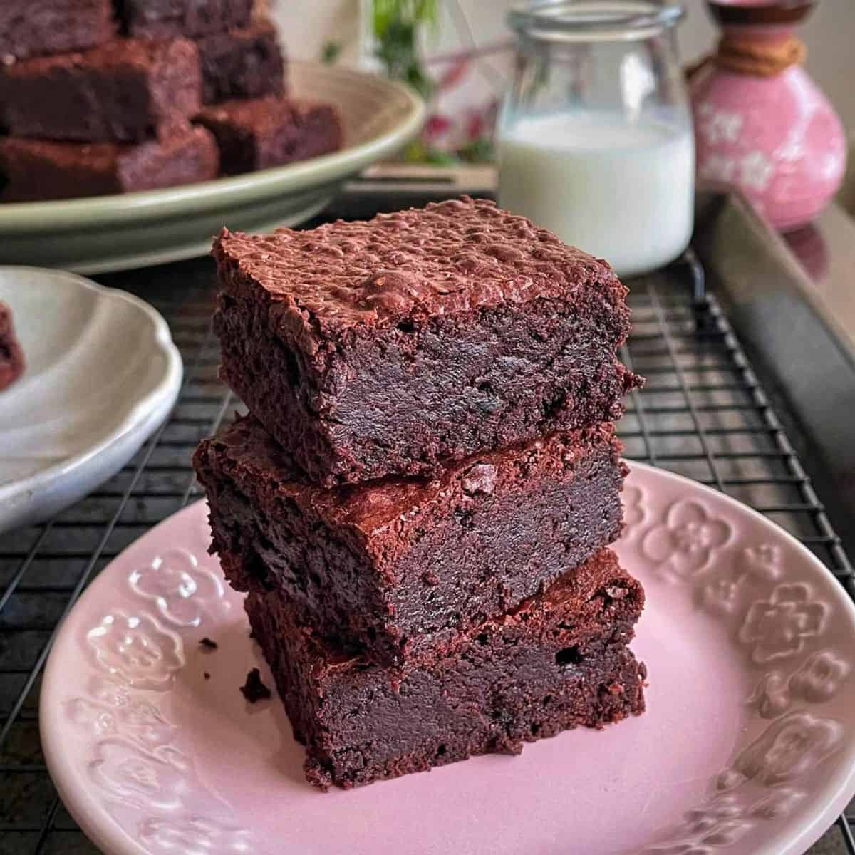 three pieces of brownie bars stacked in a dessert plate.