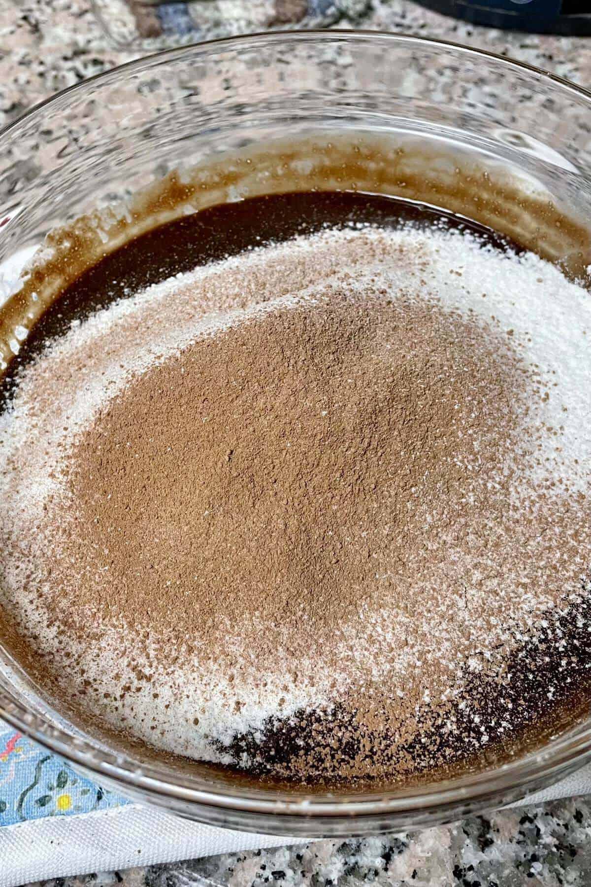 Sifted flour and cocoa powder over the brownie batter bowl.