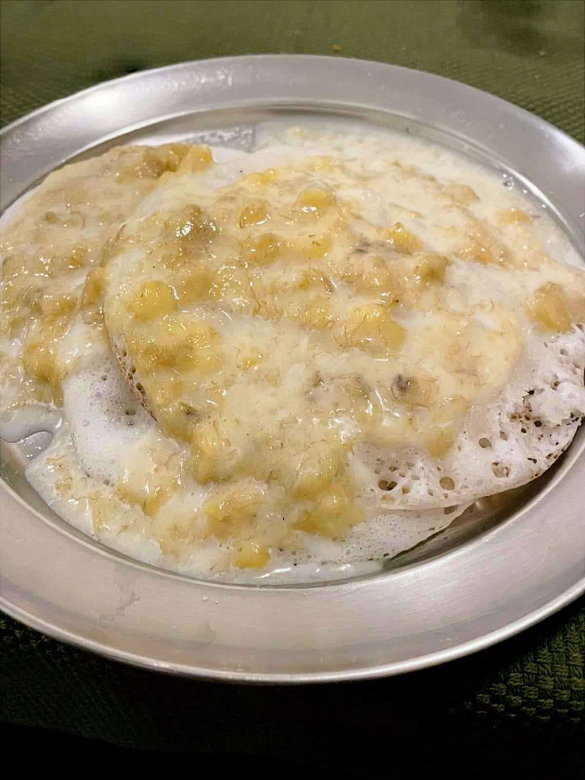 vellayappam topped with sweetened milk and mashed banana mix.