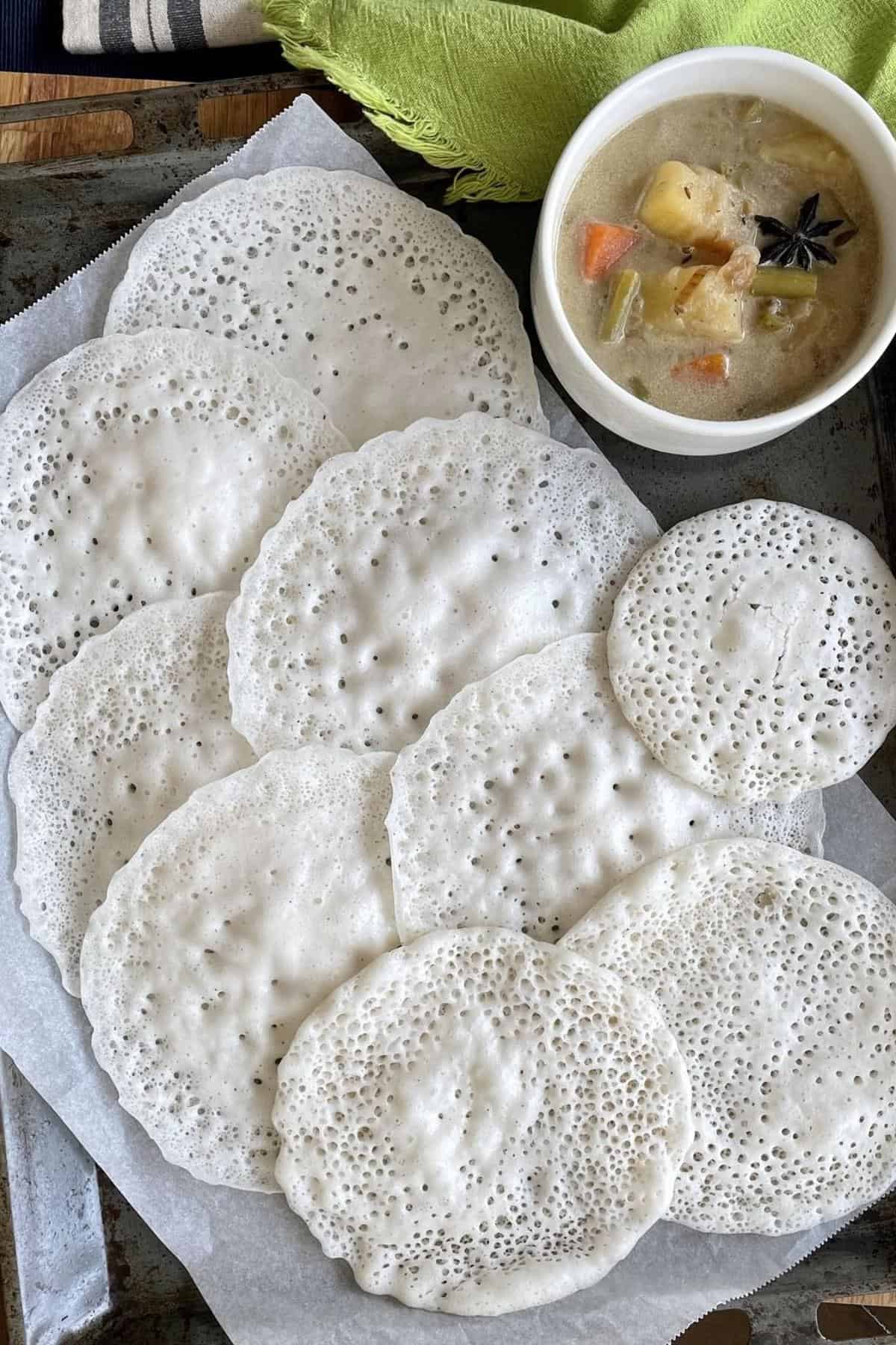 vellayappam in a tray with a bowl of stew.