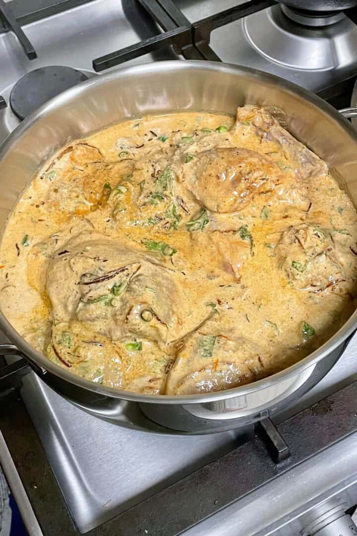 Marinated chicken in saucepot over stove.