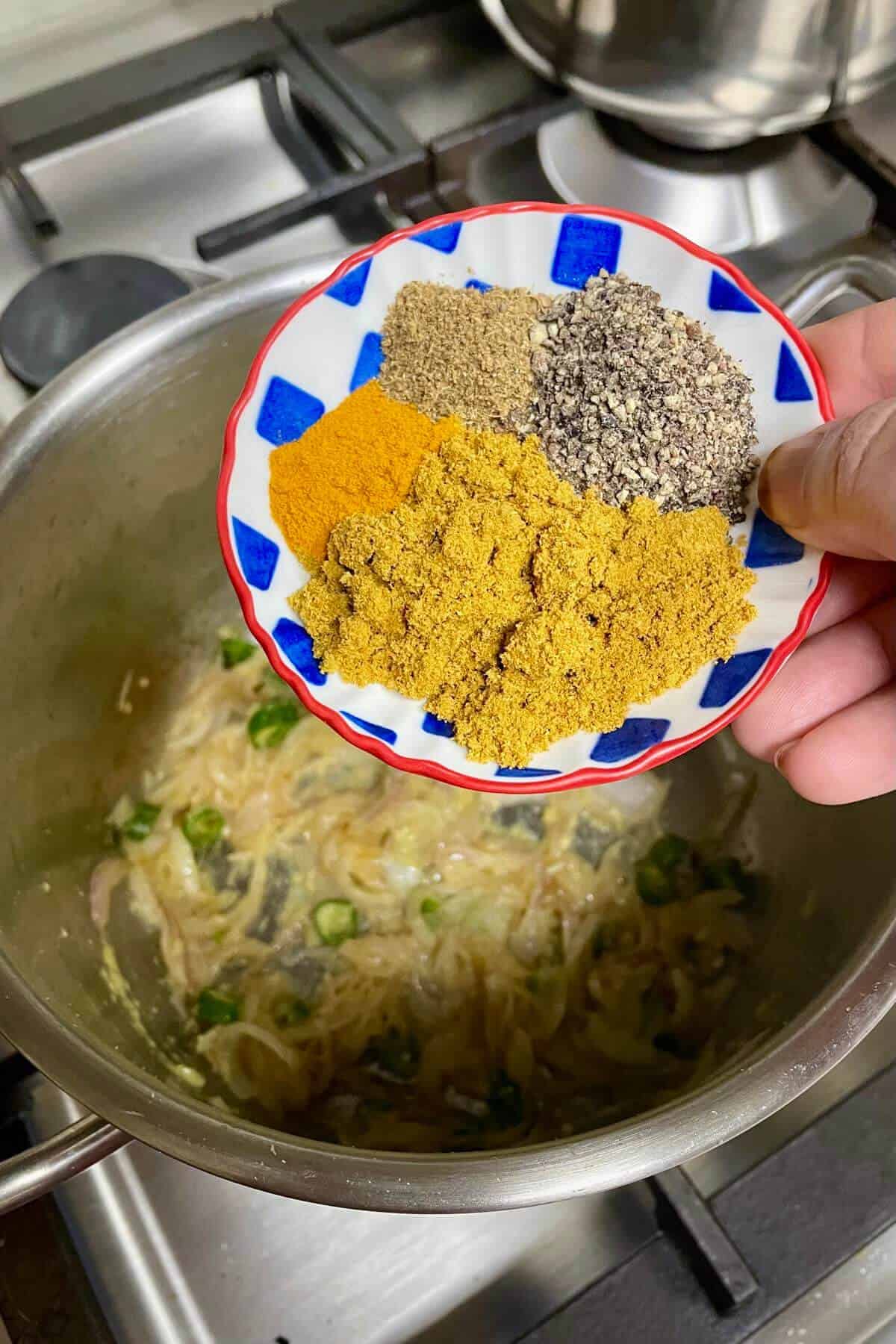A small bowl with ground spices to be added to the saucepot. 