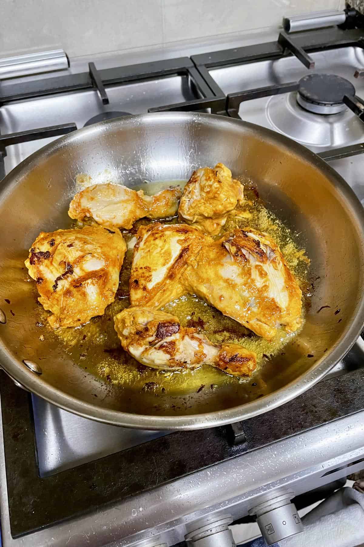 pan-searing the marinated chicken in a shallow pan.
