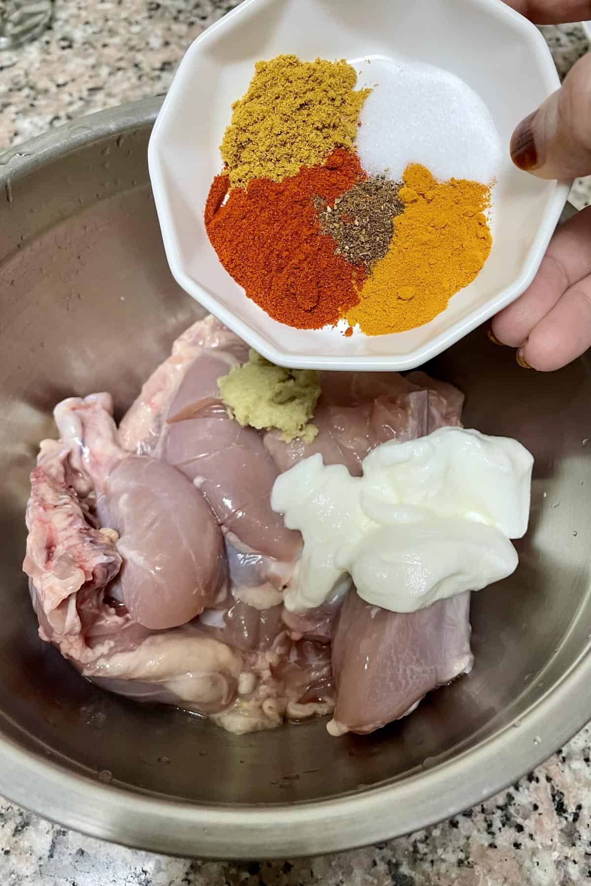 Chicken pieces in a bowl with marination ingredients.