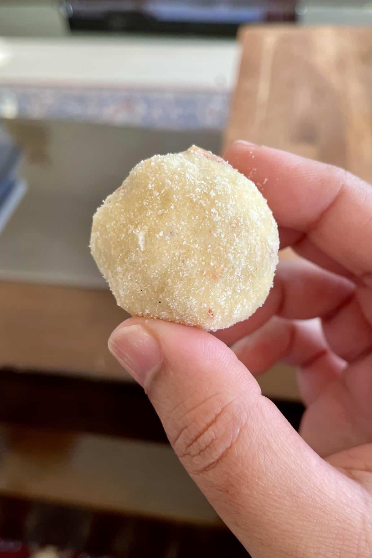 A picture of holding one rava laddu between my thumb and forefinger.