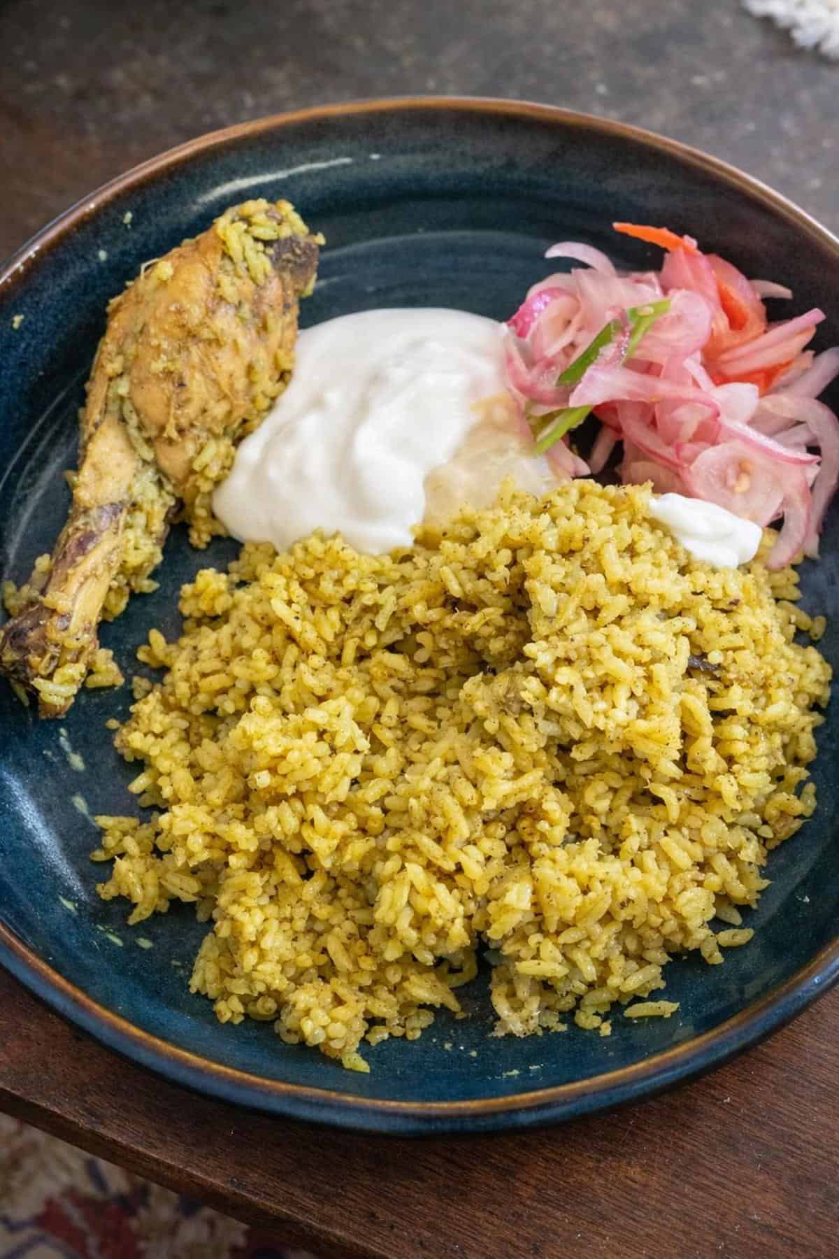 chicken donne biryani served with onion and yoghurt.