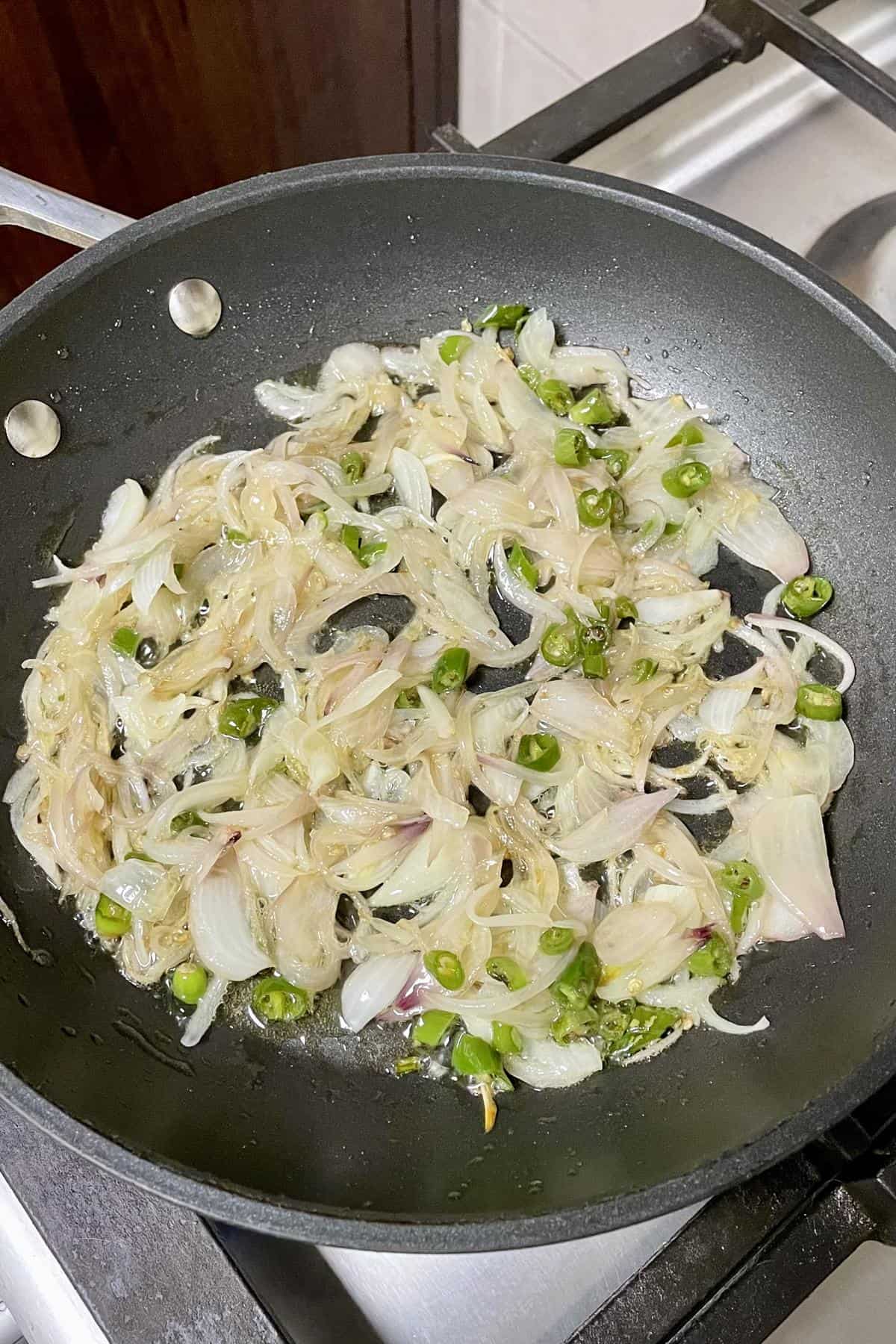 Sliced onions sauted in a shallow fry pan along with green chillies.