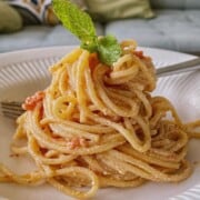 A serving of baked feta pasta garnished with mint leaf