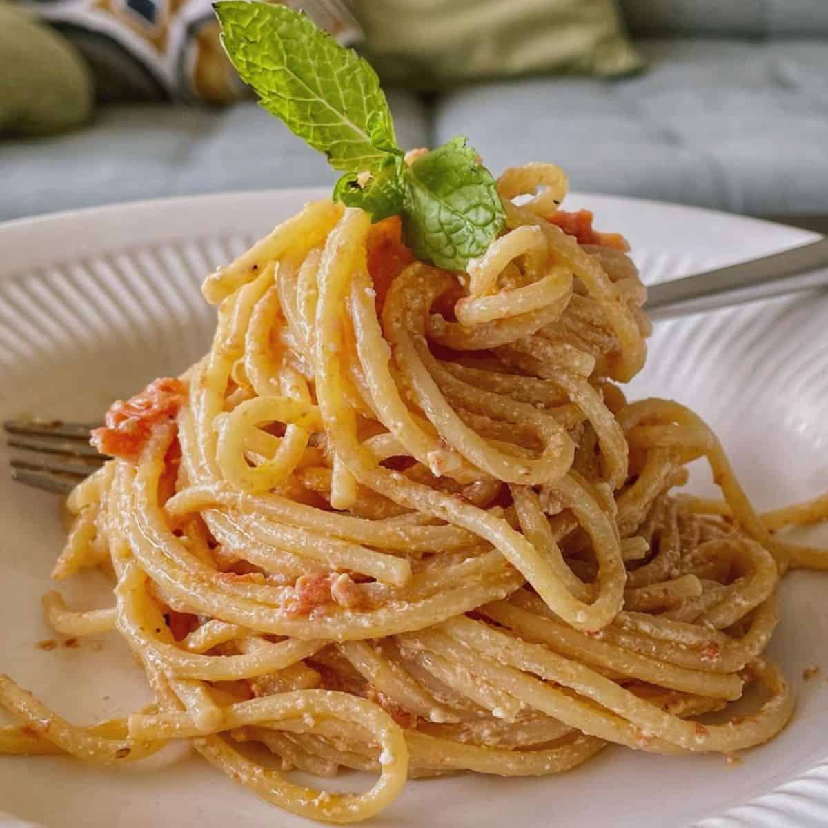 A serving of baked feta pasta garnished with mint leaf