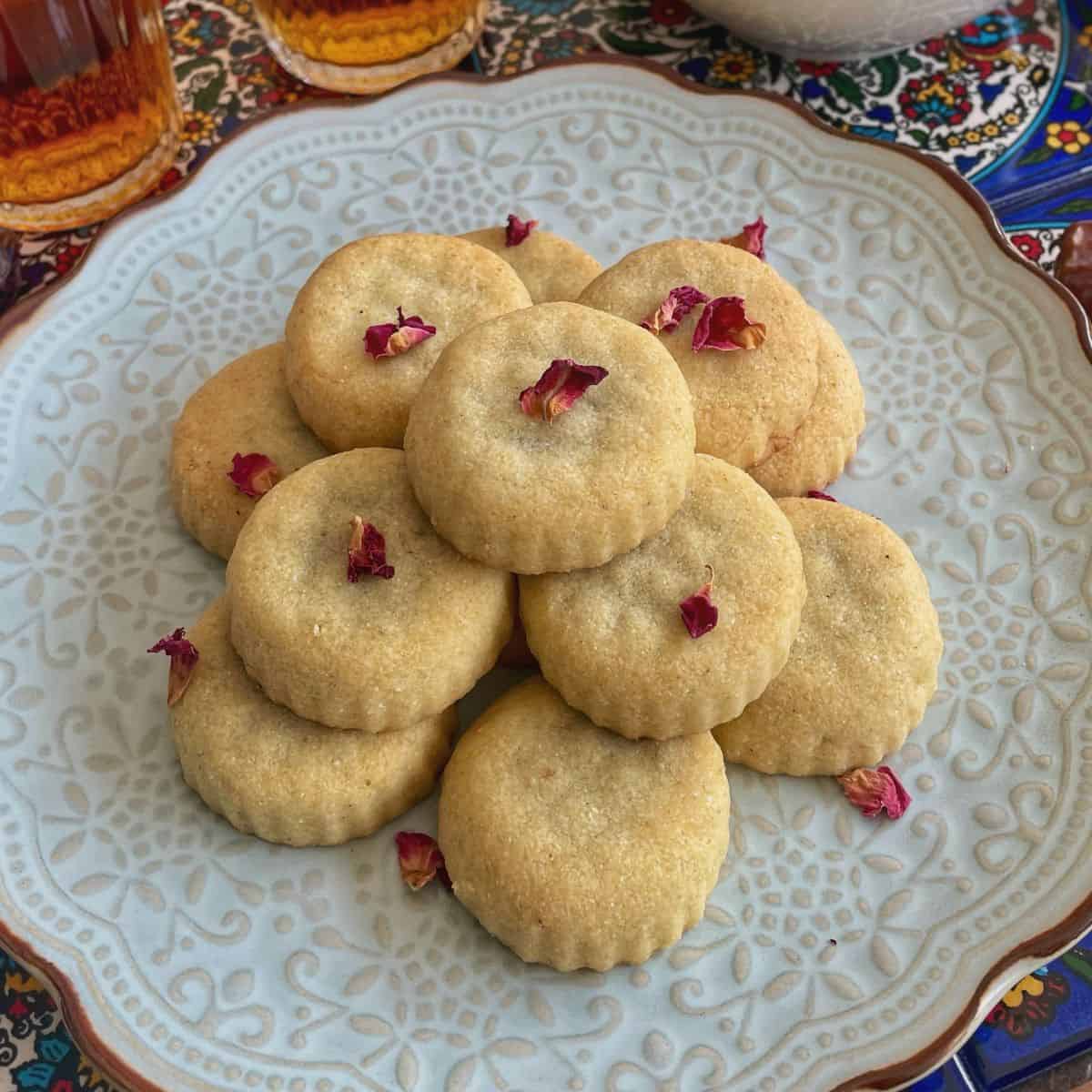 A stack of maamoul in a plate with some dried rose petals garnish.