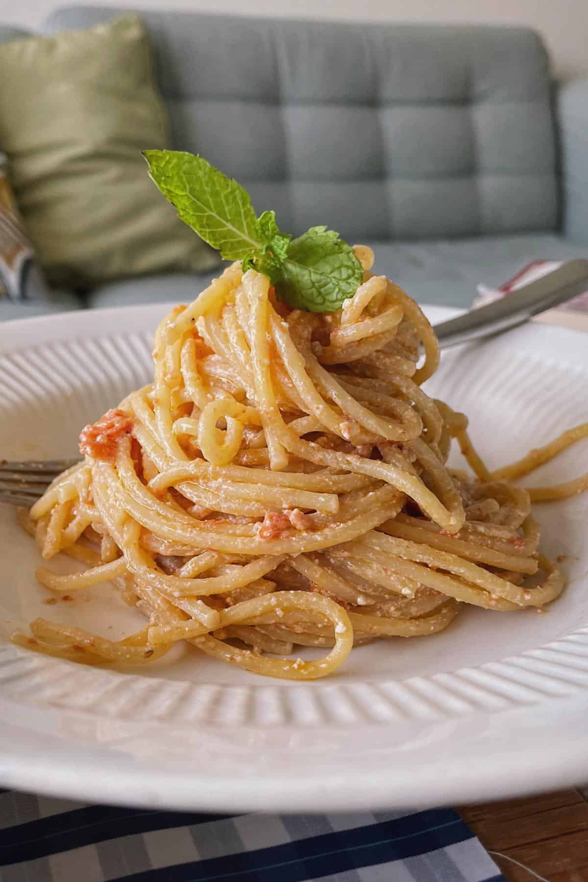 A portion served spaghetti in baked feta and tomato sauce.