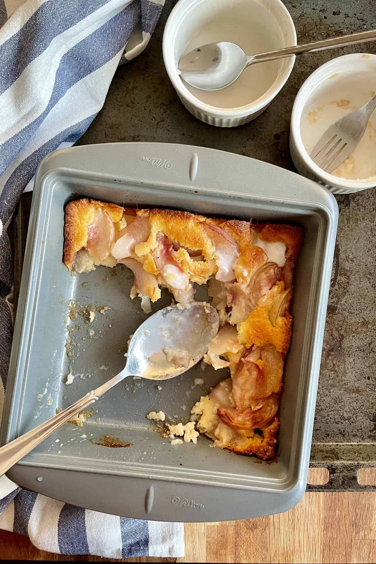 Half consumed cobbler in a baking dish with two serving bowls that had the serving.