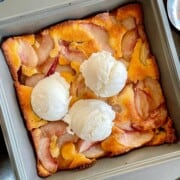 Baked fresh necatrine cobbler with ice cream scoops on it.