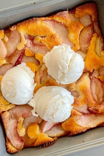 Baked fresh necatrine cobbler with ice cream scoops on it.