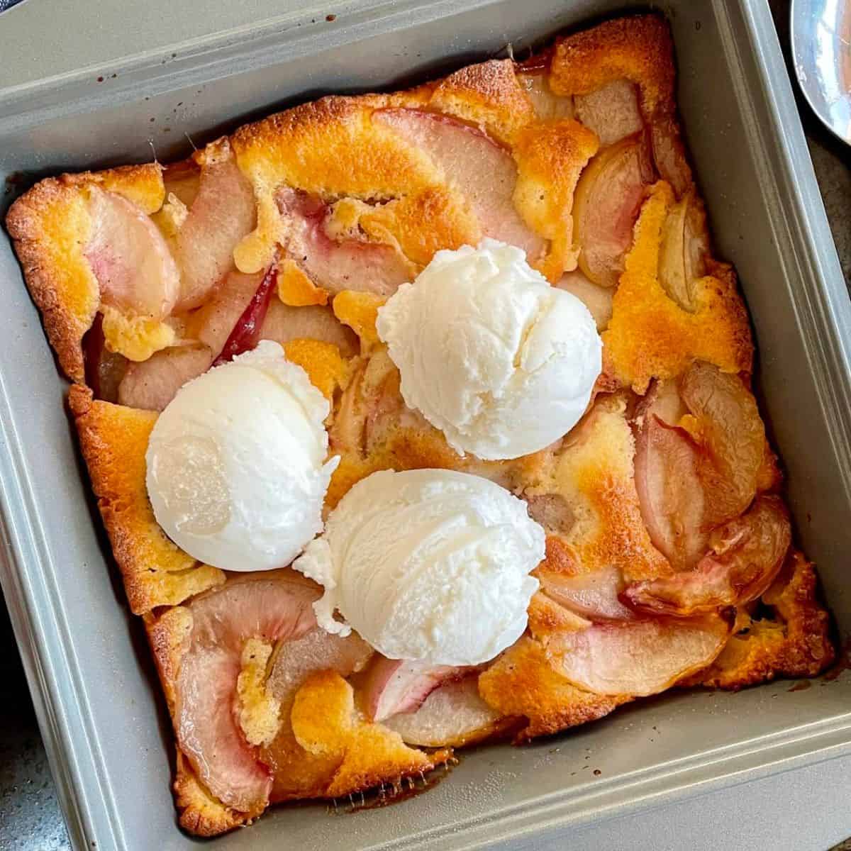 Baked fresh necatrine cobbler with ice cream scoops on it.